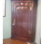 A George III oak handing corner cupboard, with fielded panel door enclosing shaped shelves.