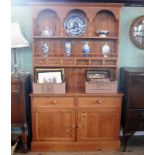 A contemporary tall pine dresser, having rack with open shelves and spice drawers,