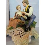 A Continental porcelain figure group of a courting couple seated,