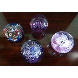 A collection of four glass paperweights, to include one Caithness example.