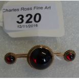 A yellow metal bar brooch set with a large ruby coloured circular garnet,