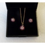 A ruby and diamond cluster pendant and a 9 carat gold chain, together with matching earrings.