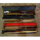 Four snooker/pool cues in fitted cases.