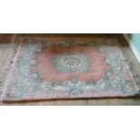 A Chinese-style rug with floral decoration on a salmon pink ground (190cm x 122cm).