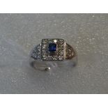A white metal Art Deco-style ring, possibly 18 carat gold, set with central square cut sapphire,
