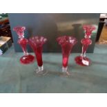 A pair of cranberry glass candlesticks, together with a pair of cranberry trumpet vases.