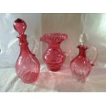 Three pieces of cranberry coloured glass, to include: a baluster jug with frilled neck,