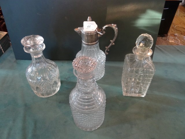 Three glass decanters, together with a glass claret jug with white metal mounts.