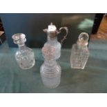 Three glass decanters, together with a glass claret jug with white metal mounts.