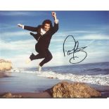 Paul Young signed 10 x 8 inch colour photo of him jumping on a beach.  Formerly the frontman of