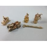 A small collection of quirky gold charms, the first a helter-skelter with hinged base revealing an