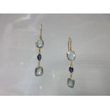 A pair of aquamarine and sapphire earpendants, each wire hook suspending an articulated line of