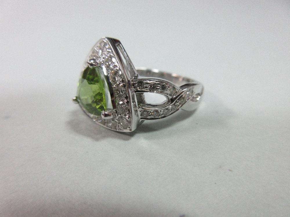 A contemporary peridot and diamond ring, the triangular cut peridot in a border of round brilliant - Image 3 of 7