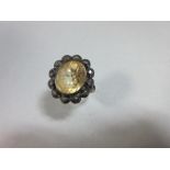 A yellow topaz and diamond cluster ring, the oval cut pale yellow topaz in a border of tiny