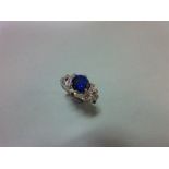 A synthetic sapphire and diamond ring, the round cut royal blue sapphire between shoulders with