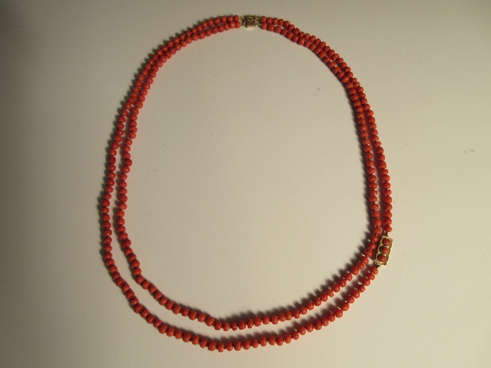 A two row red coral bead necklace, the uniform 5-6mm diameter tyre-shaped beads, individually