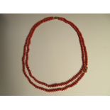 A two row red coral bead necklace, the uniform 5-6mm diameter tyre-shaped beads, individually