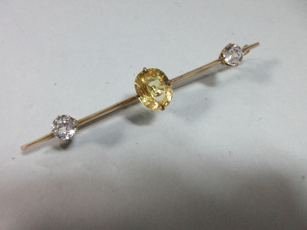 A yellow sapphire and white sapphire bar brooch, claw set to the centre of the knife-edge bar with