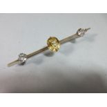 A yellow sapphire and white sapphire bar brooch, claw set to the centre of the knife-edge bar with