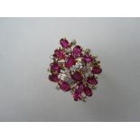 A modern ruby and diamond cluster ring, designed as a pierced asymmetric loose cluster of diaper