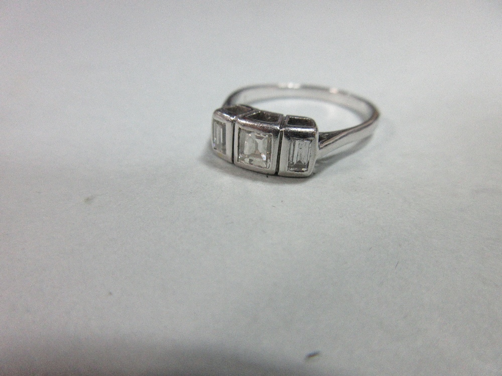 A step cut diamond three stone ring, the graduated rectangular diamonds collet set in unmarked white - Image 2 of 5