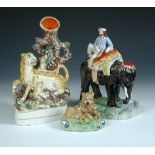 Three 19th century Staffordshire pottery figures, the 'Walton' lion reclining on a green mound,