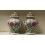 A pair of Chinese famille rose jars and covers, the baluster sides painted with peonies growing