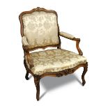A Louis XV carved beechwood framed armchair, carved with acanthus leaf and fleurette, upholstered
