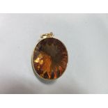 A fancy cut citrine pendant, the large oval dark golden citrine with harlequin faceted crown and