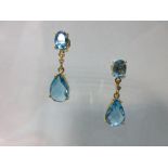 A pair of blue topaz earpendants with diamond highlights, each post headed by an oval cut blue topaz