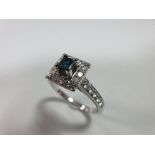 A diamond and treated blue diamond cluster ring, set to the centre with a princess cut teal blue
