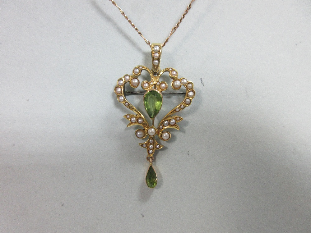 An Edwardian peridot and seed pearl pendant/brooch with chain, the open heart-shaped pendant with