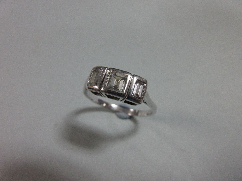A step cut diamond three stone ring, the graduated rectangular diamonds collet set in unmarked white