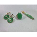 A jade ring, a pin brooch and a pair of earpendants, the ring with an oval cabochon jade claw set to