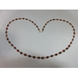 A garnet line necklace, composed of fifty graduated oval cut garnets, spectacle set and joined by
