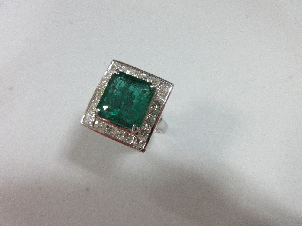 A large emerald and diamond cluster ring, the emerald cut emerald, estimated weight 4.78cts, above a