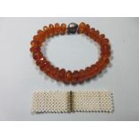 A vintage amber bead necklace and a pearl choker, the amber necklace a graduated string of 17-27mm