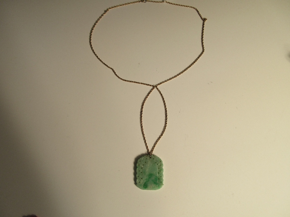 A carved jadeite jade pendant on a ropetwist chain, the mottled light green jade plaque carved on