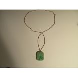 A carved jadeite jade pendant on a ropetwist chain, the mottled light green jade plaque carved on