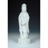 An 18th/19th century blanc de Chine Guanyin standing on a cloud base with hands crossed at the