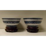 A pair of 19th century Chinese blue and white bowls and wood stands, the exteriors painted with a