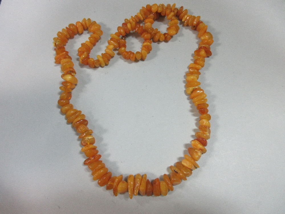 A butterscotch amber bead necklace, of graduated randomly shaped 'pebble' beads, gross weight 41.8g,