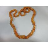 A butterscotch amber bead necklace, of graduated randomly shaped 'pebble' beads, gross weight 41.8g,