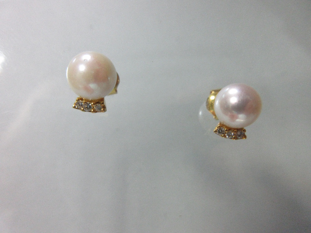 A pair of pearl and diamond earstuds, each post headed by a 7mm pearl above a short curved line