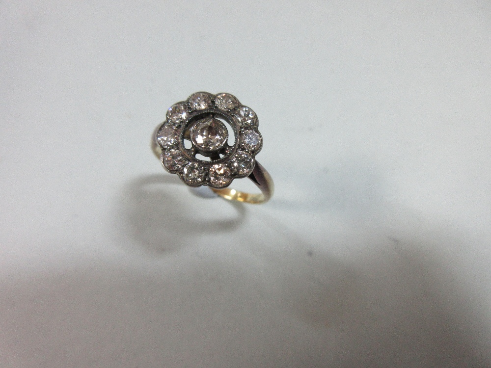 A diamond pierced cluster ring, with a central millegrain collet set round brilliant cut diamond