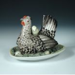 A late 19th/early 20th century Volkstedt porcelain basket and cover, modelled as a hen with four