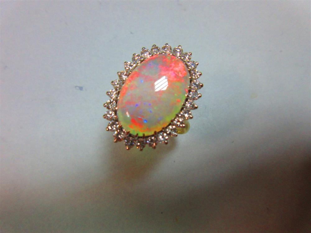 An opal and diamond cluster ring, the 17mm long oval cabochon opal, displaying good predominantly