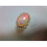 An opal and diamond cluster ring, the 17mm long oval cabochon opal, displaying good predominantly