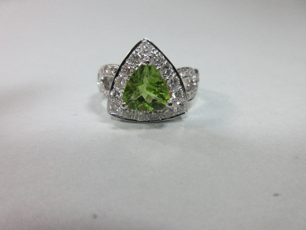 A contemporary peridot and diamond ring, the triangular cut peridot in a border of round brilliant - Image 2 of 7