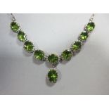 A peridot necklace, set to the front with a line of nine graduated oval cut peridots with a tenth,